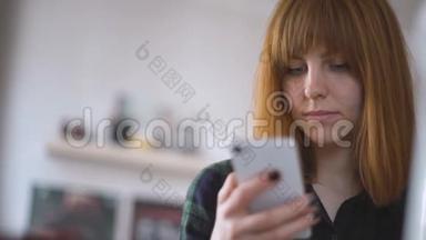 年轻漂亮的红发女郎在家里使用智能手机